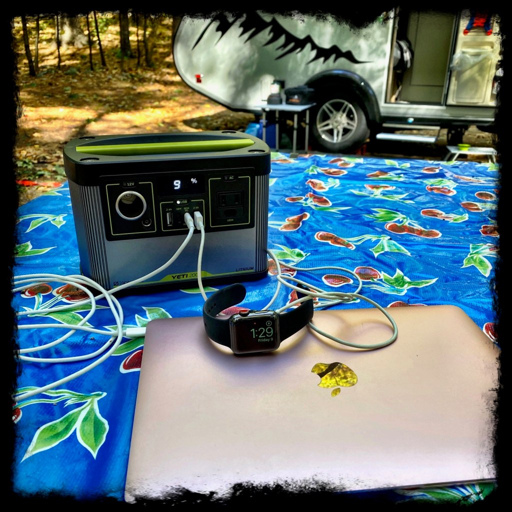 GoalZero Yet with Mac laptop and Apple Watch plugged in to charge on a picnic table near the camper