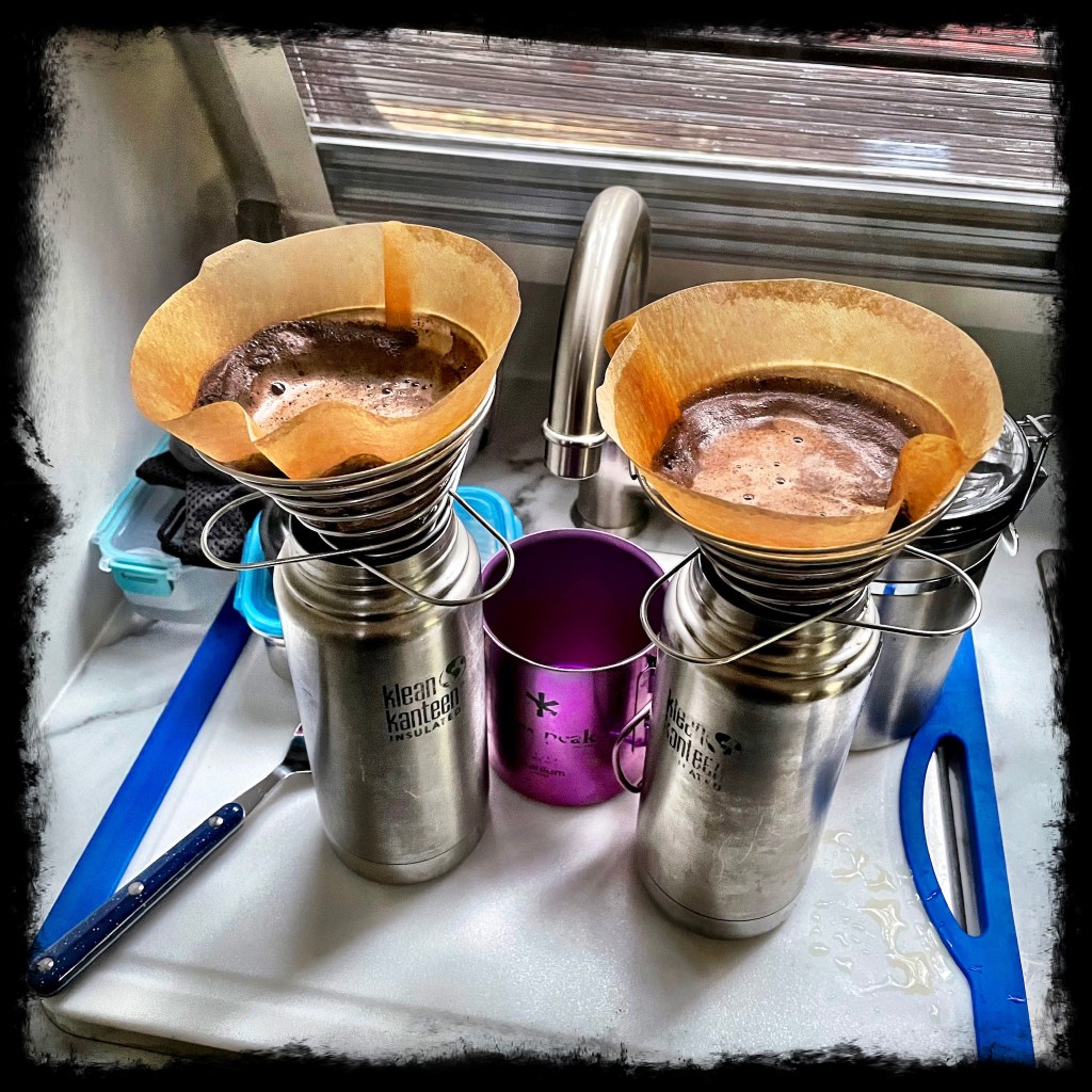 Two klean kanteen bottles on the counter in the camper with pourover coffee being made