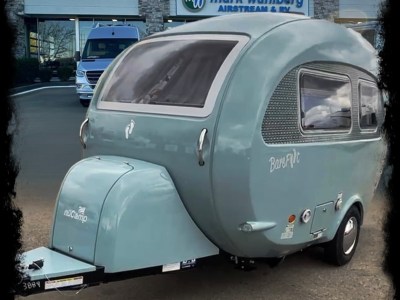 A seaglass Barefoot Caravan from the driver's side sitting in front of an RV dealership.