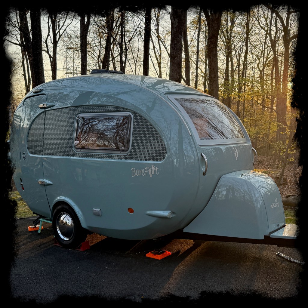 Photograph of a eggshell blue Barefoot Caravan in the glow of morning sun.
